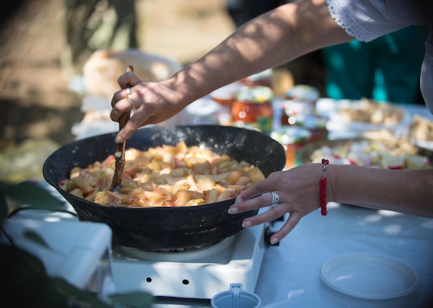 Une femme prépare de la confiture de pommes en vacances à l'extérieur en été