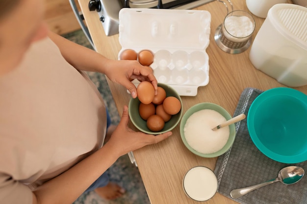 La femme prépare les œufs pour la nourriture sur la table