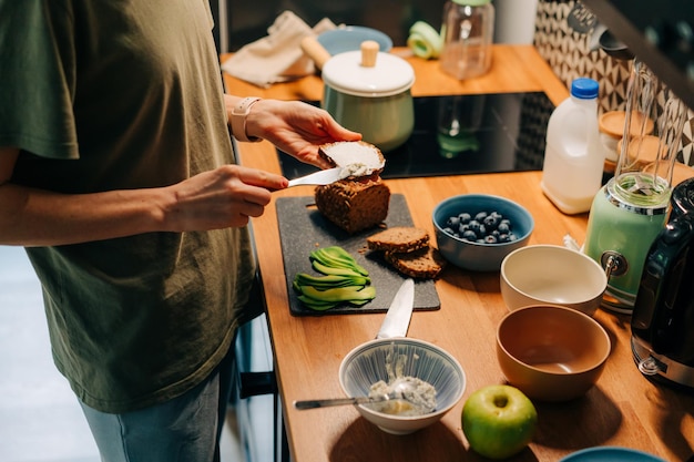 Une femme prépare un sandwich dans la cuisine.
