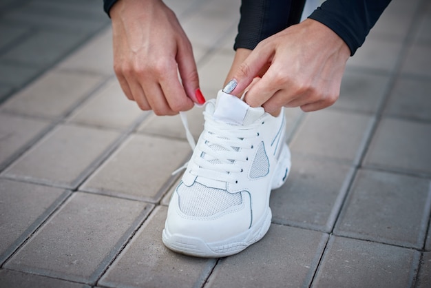 Femme préparez-vous à courir. Mains féminines attachant des lacets sur des baskets de sport