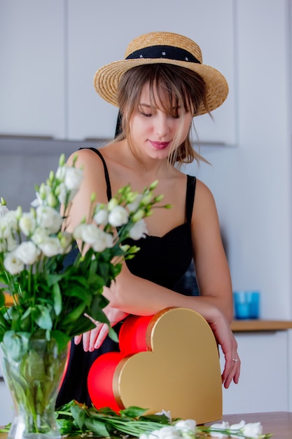 femme près de bouquet de roses blanches dans un vase et une boîte cadeau