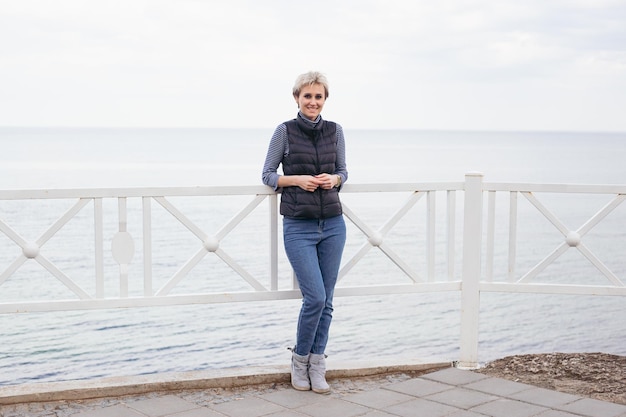 Femme près de la mer Modèle féminin aux cheveux courts ayant une promenade par temps nuageux Nature concept de temps libre