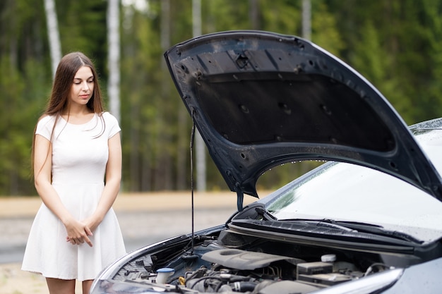 Femme près de voiture cassée à sous le capot ouvert