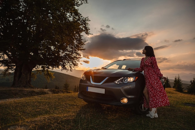 Femme près de voiture Coucher de soleil dans les montagnes