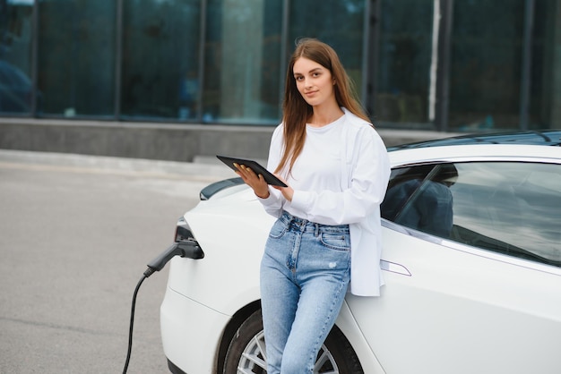 Femme près d'une voiture électrique Véhicule chargé à la borne de recharge