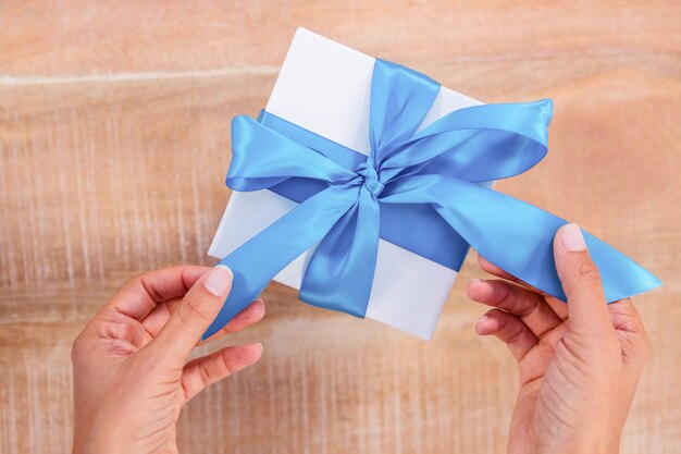 Femme présentant un cadeau avec un ruban bleu sur le bureau