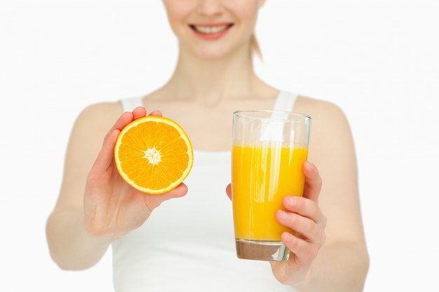 Femme présentant une orange tout en tenant un verre