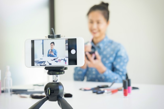 Femme présente produit de beauté et diffusion de vidéo en direct sur le réseau social par Internet à la maison, concept de blogueur de beauté.