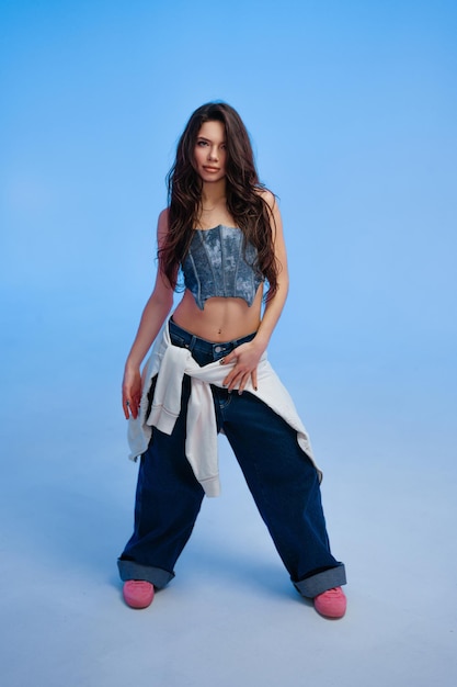 Une femme présente une tenue élégante en denim et une forme décontractée en studio