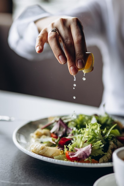 Photo femme pressant du citron sur la salade