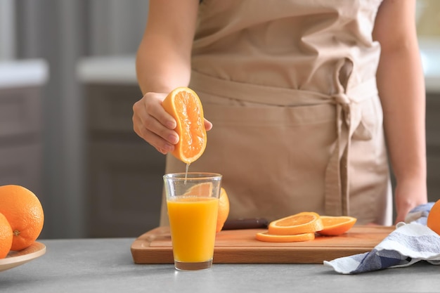 Femme pressant le jus d'orange mûre dans la cuisine