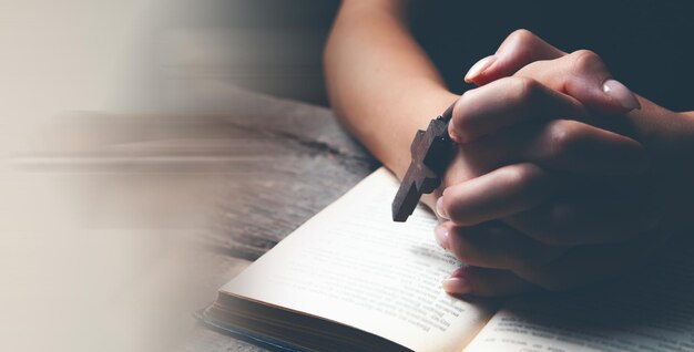 Femme priant sur le livre tenant la croix