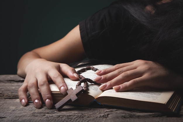 Femme priant sur le livre tenant la croix