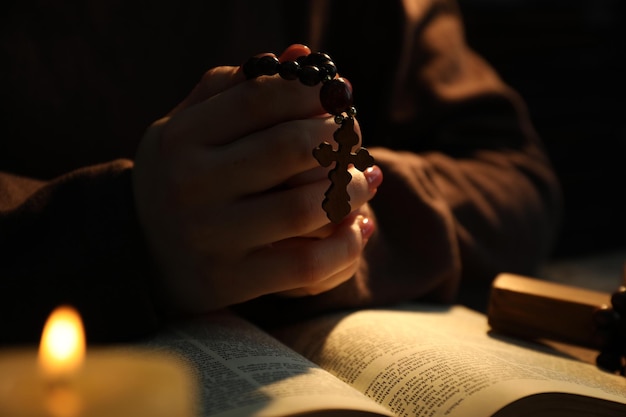 Une femme prie à table avec une bougie allumée et une Bible en gros plan