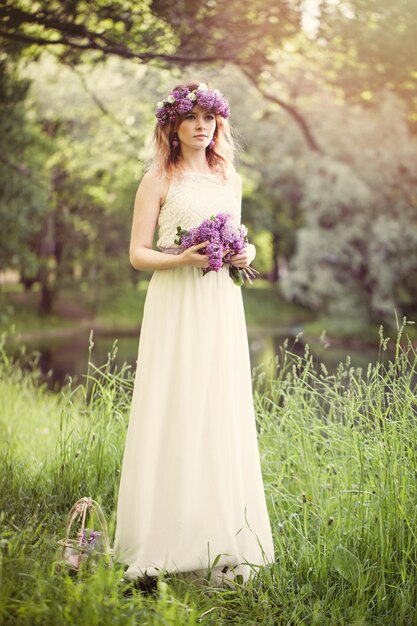 Femme de printemps en robe blanche dans l'herbe verte et les feuilles dans le parc du printemps