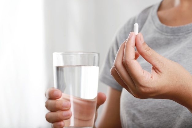 La femme a pris une pilule et a suivi avec un verre d'eau.