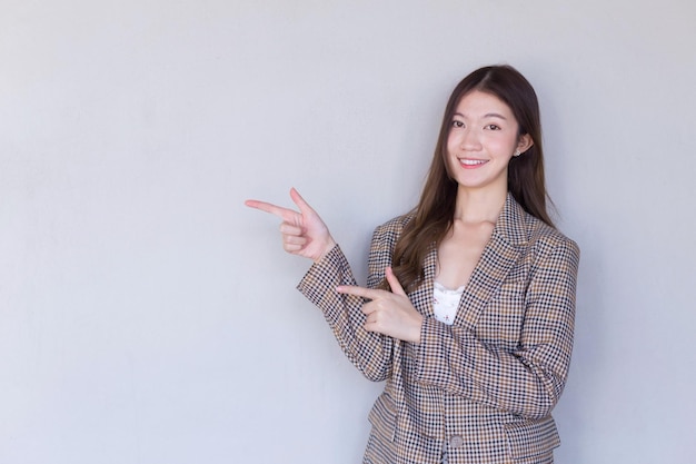 Femme professionnelle asiatique aux cheveux longs noirs portant un costume à carreaux et assez souriante