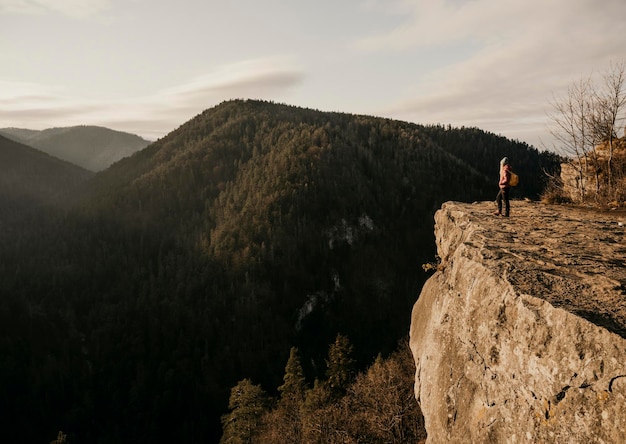 Femme profitant du coucher de soleil dans la nature au bord d'une falaise rocheuse