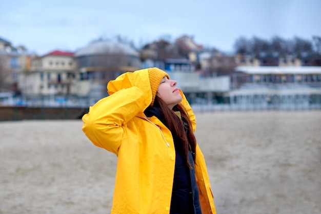 Femme profitant d'une journée d'hiver sur la plage respirant joyeusement l'air frais de la mer