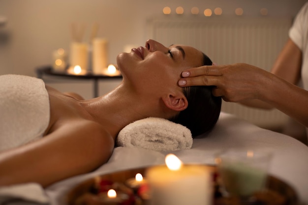 Une femme profitant d'un massage relaxant de la tête contre le stress et d'un pampering dans un salon d'ambiance chaud à la lumière de bougies