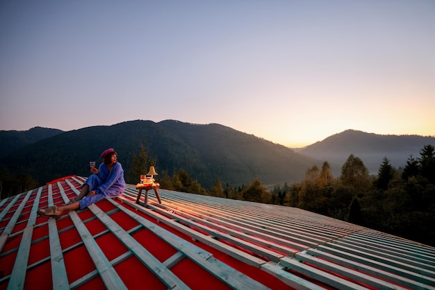 Une femme profite d'un beau coucher de soleil dans les montagnes