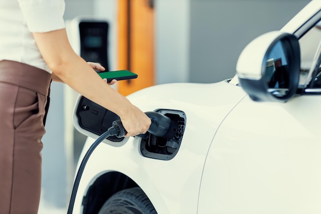 Une femme progressiste en gros plan recharge sa voiture EV à la station de charge à domicile