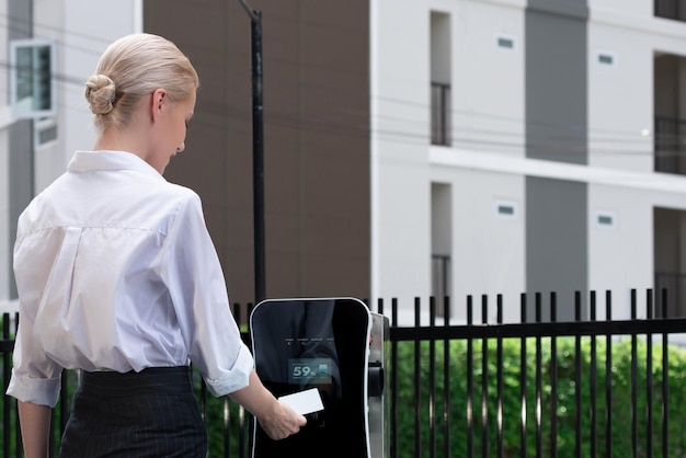 Une femme progressiste paie pour un point de recharge pour alimenter un véhicule électrique rechargeable