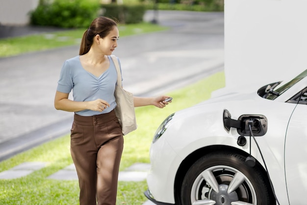 Une femme progressiste recharge sa voiture EV à la station de charge à domicile