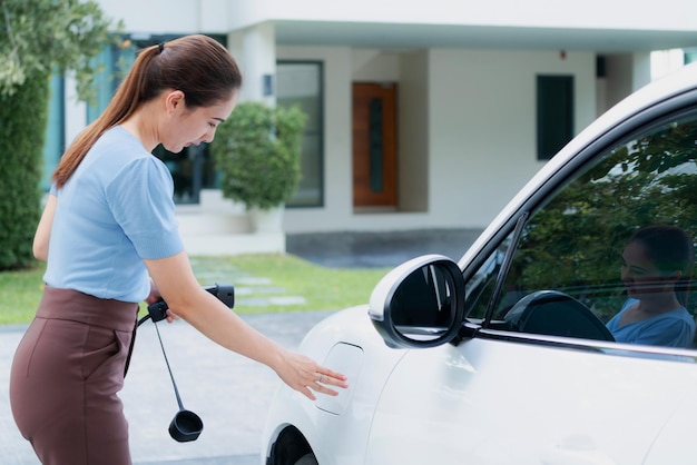 Une femme progressiste recharge sa voiture EV à la station de charge à domicile