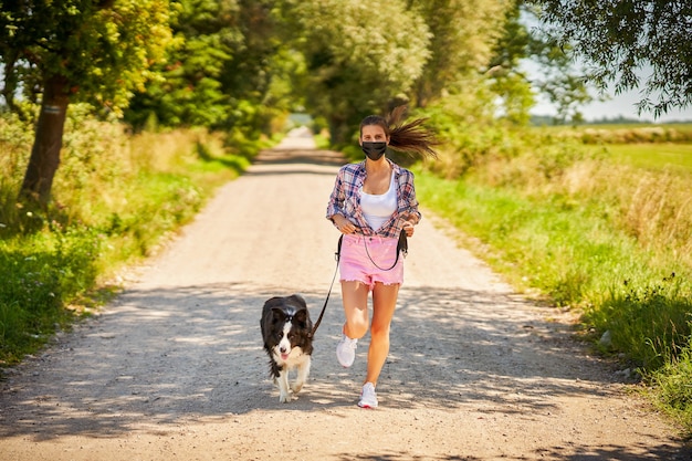 femme promenant un chien dans la campagne et portant un masque