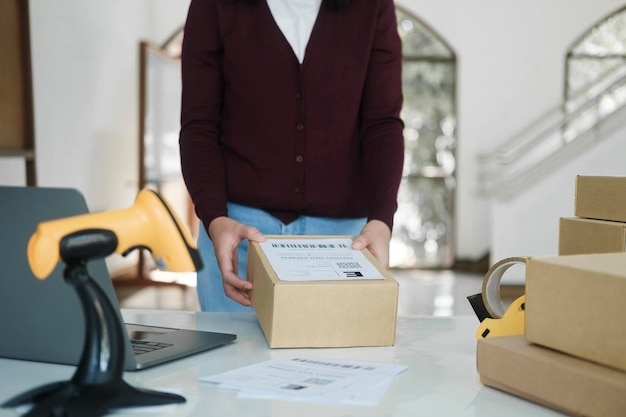 Femme propriétaire d'une boutique en ligne mettant une étiquette sur un colis