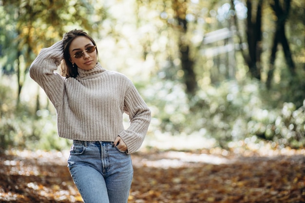 Femme en pull chaud marchant dans le parc d'automne