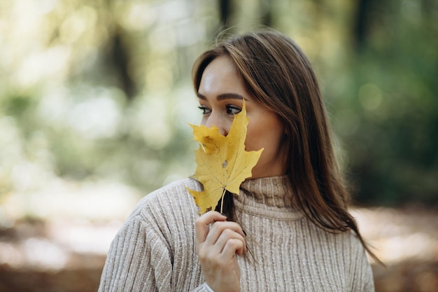 Femme en pull chaud marchant dans le parc d'automne