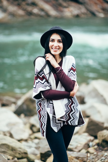 Femme en pull chaud marchant le long d'une rivière de montagne