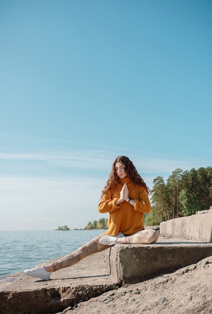 Femme en pull orange assis sur un escalier en pierre sur une plage