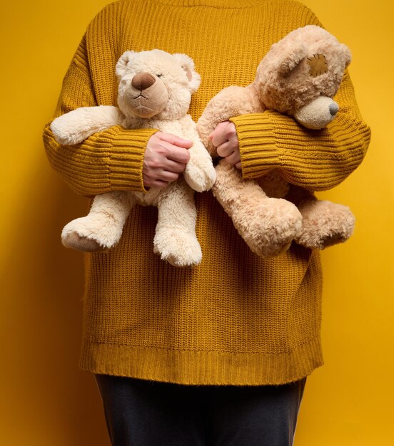 Femme en pull orange étreint un mignon ours en peluche marron