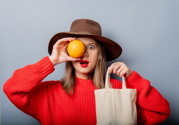 Femme en pull rouge avec orange et sac