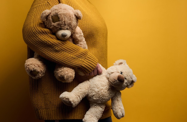 Une femme en pull tricoté orange embrasse un joli ours en peluche marron. Le concept de solitude et de tristesse, de dépression