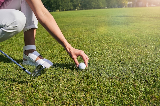 une femme avec un putter plaçant une balle de golf sur le sol