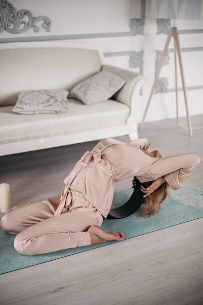 Femme En Pyjama Assise Sur Le Tapis Et Faisant Un Backbend Pendant Les Exercices Du Matin à La Maison. Concept De Mode De Vie Sain. Remise En Forme Du Matin