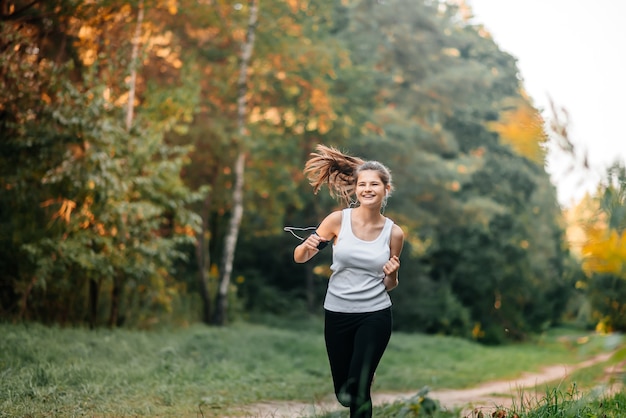 Photo femme qui court dans la forêt d'automne d'automne. mode de vie sain . ajuster le modèle de remise en forme ethnique du caucase.