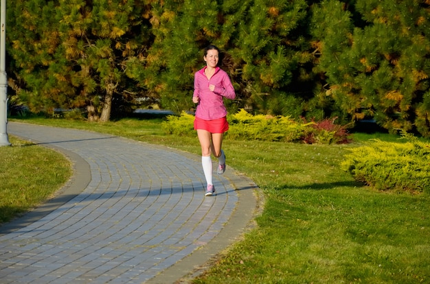 Femme qui court dans le parc automne, coureur de belle fille jogging en plein air. exercice et concept de remise en forme