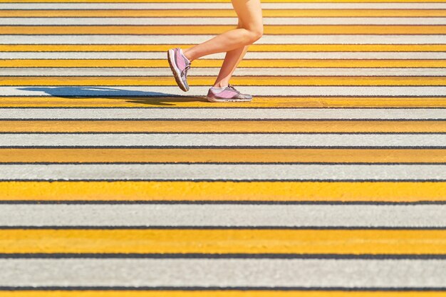 Femme qui court pour passage pour piétons, copiez l'espace. Femme athlétique jogging en tenue de sport sur route de la ville. Mode de vie sain, passe-temps de sport de remise en forme. Violation du code de la route. Entraînement de rue, sprint en plein air