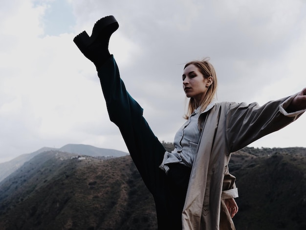 Une femme qui donne des coups de pied alors qu'elle se tient sur une montagne contre le ciel