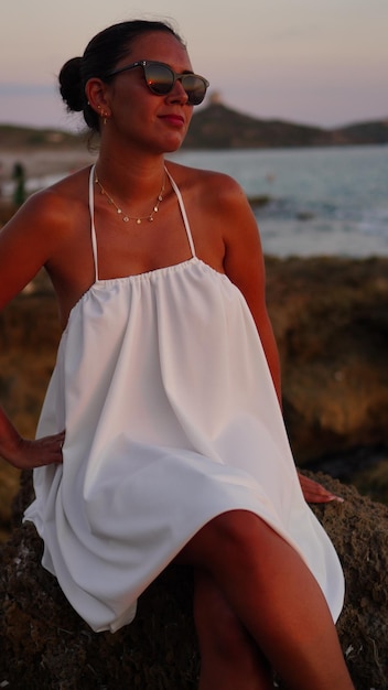 Photo une femme qui lit au coucher du soleil sur la côte rocheuse aime un livre