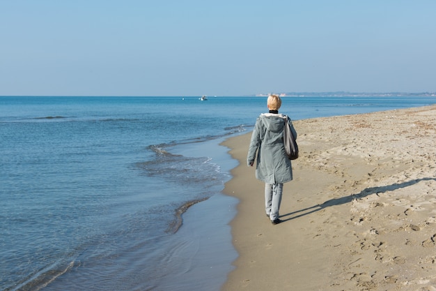 Femme qui marche au bord de la mer en hiver