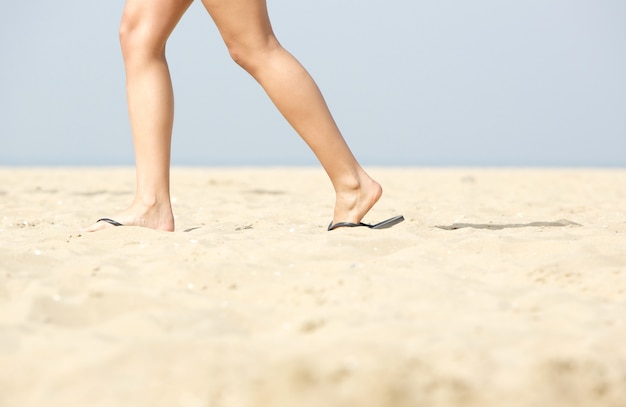 Femme qui marche dans les sandales sur le sable