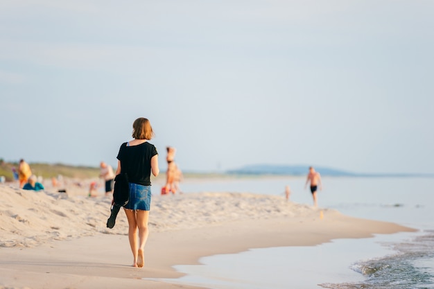 Femme qui marche le long de la plage en été.