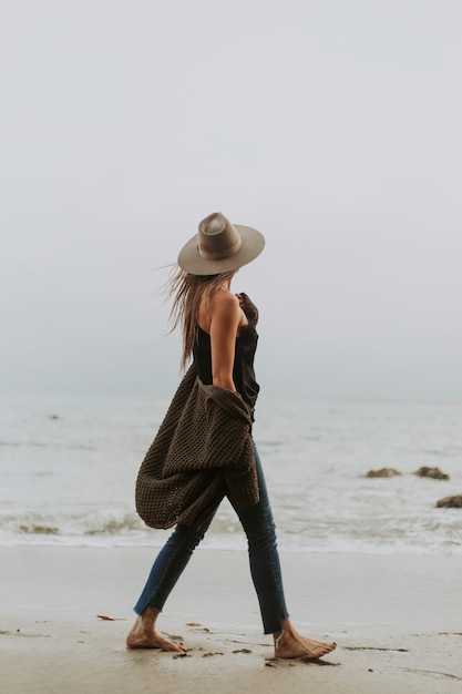 Femme qui marche pieds nus sur la plage