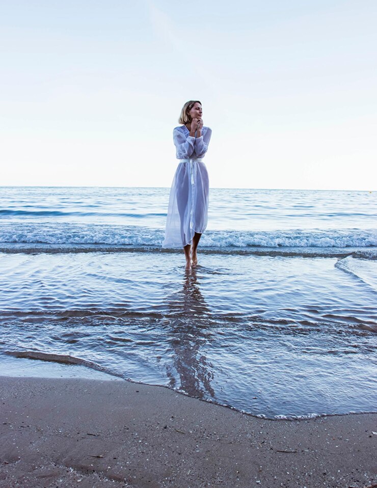 Photo une femme qui marche sur la plage contre le ciel